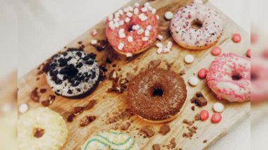 Çikolata, marşmelov ve retro pişirme tepsisindeki şekerli çörekler. Donutlar doğal çikolatayla süslenmiş bir kağıdın üzerinde. Makro ve kaydırma atışı. Çeşitli renkli çörekler. Çikolata, pembe, mavi çörekler