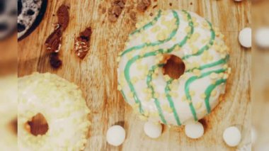 Çikolata, marşmelov ve retro pişirme tepsisindeki şekerli çörekler. Donutlar doğal çikolatayla süslenmiş bir kağıdın üzerinde. Makro ve kaydırma atışı. Çeşitli renkli çörekler. Çikolata, pembe, mavi çörekler