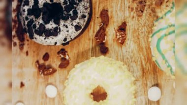 Çikolata, marşmelov ve retro pişirme tepsisindeki şekerli çörekler. Donutlar doğal çikolatayla süslenmiş bir kağıdın üzerinde. Makro ve kaydırma atışı. Çeşitli renkli çörekler. Çikolata, pembe, mavi çörekler