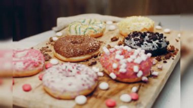 Çikolata, marşmelov ve retro pişirme tepsisindeki şekerli çörekler. Donutlar doğal çikolatayla süslenmiş bir kağıdın üzerinde. Makro ve kaydırma atışı. Çeşitli renkli çörekler. Çikolata, pembe, mavi çörekler