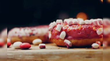 Çikolata, marşmelov ve retro pişirme tepsisindeki şekerli çörekler. Donutlar doğal çikolatayla süslenmiş bir kağıdın üzerinde. Makro ve kaydırma atışı. Çeşitli renkli çörekler. Çikolata, pembe, mavi çörekler