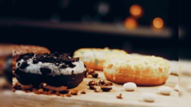 Çikolata, marşmelov ve retro pişirme tepsisindeki şekerli çörekler. Donutlar doğal çikolatayla süslenmiş bir kağıdın üzerinde. Makro ve kaydırma atışı. Çeşitli renkli çörekler. Çikolata, pembe, mavi çörekler