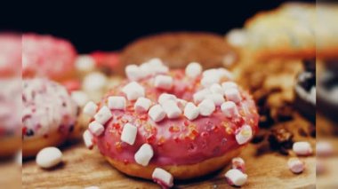 Çikolata, marşmelov ve retro pişirme tepsisindeki şekerli çörekler. Donutlar doğal çikolatayla süslenmiş bir kağıdın üzerinde. Makro ve kaydırma atışı. Çeşitli renkli çörekler. Çikolata, pembe, mavi çörekler