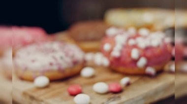 Çikolata, marşmelov ve retro pişirme tepsisindeki şekerli çörekler. Donutlar doğal çikolatayla süslenmiş bir kağıdın üzerinde. Makro ve kaydırma atışı. Çeşitli renkli çörekler. Çikolata, pembe, mavi çörekler