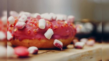 Çikolata, marşmelov ve retro pişirme tepsisindeki şekerli çörekler. Donutlar doğal çikolatayla süslenmiş bir kağıdın üzerinde. Makro ve kaydırma atışı. Çeşitli renkli çörekler. Çikolata, pembe, mavi çörekler