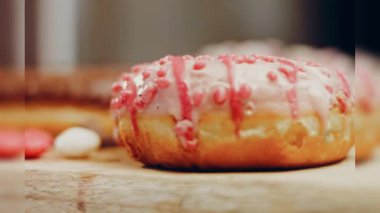 Çikolata, marşmelov ve retro pişirme tepsisindeki şekerli çörekler. Donutlar doğal çikolatayla süslenmiş bir kağıdın üzerinde. Makro ve kaydırma atışı. Çeşitli renkli çörekler. Çikolata, pembe, mavi çörekler