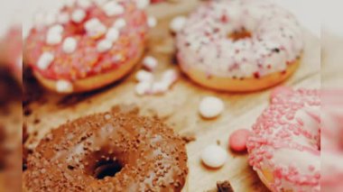 Çikolata, marşmelov ve retro pişirme tepsisindeki şekerli çörekler. Donutlar doğal çikolatayla süslenmiş bir kağıdın üzerinde. Makro ve kaydırma atışı. Çeşitli renkli çörekler. Çikolata, pembe, mavi çörekler