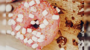 Çikolata, marşmelov ve retro pişirme tepsisindeki şekerli çörekler. Donutlar doğal çikolatayla süslenmiş bir kağıdın üzerinde. Makro ve kaydırma atışı. Çeşitli renkli çörekler. Çikolata, pembe, mavi çörekler