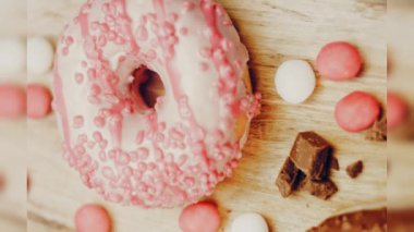 Çikolata, marşmelov ve retro pişirme tepsisindeki şekerli çörekler. Donutlar doğal çikolatayla süslenmiş bir kağıdın üzerinde. Makro ve kaydırma atışı. Çeşitli renkli çörekler. Çikolata, pembe, mavi çörekler