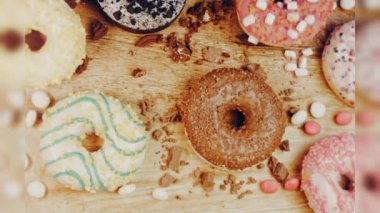 Çikolata, marşmelov ve retro pişirme tepsisindeki şekerli çörekler. Donutlar doğal çikolatayla süslenmiş bir kağıdın üzerinde. Makro ve kaydırma atışı. Çeşitli renkli çörekler. Çikolata, pembe, mavi çörekler