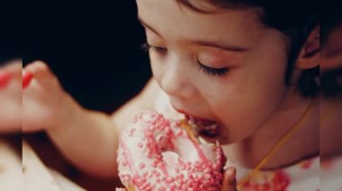 Kız hediyeler arasından seçiyor, parmağını işaret ediyor. Çikolata, marşmelov ve retro pişirme tepsisindeki şekerli çörekler. Donutlar doğal çikolatayla süslenmiş bir kağıdın üzerinde. Makro ve kaydırıcı