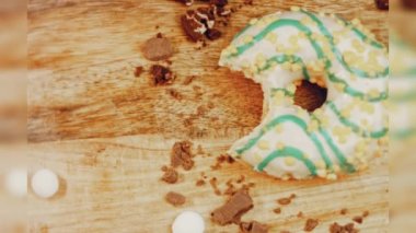 Donut 'ın ağız şeklinde bir ısırığı var. Mavi kremayla süslenmiş sarı çörekler. Çörekler şekerle süslenmiş bir kağıt parçasının üzerinde. Makro ve kaydırma atışı. Makro ve kaydırma atışı. Şekerler içeri giriyor.