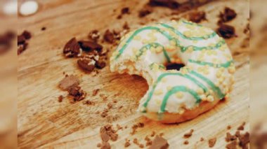 Donut 'ın ağız şeklinde bir ısırığı var. Mavi kremayla süslenmiş sarı çörekler. Çörekler şekerle süslenmiş bir kağıt parçasının üzerinde. Makro ve kaydırma atışı. Makro ve kaydırma atışı. Şekerler içeri giriyor.