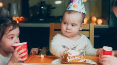 Bir yaşındaki kızların doğum günü partisi. Annem bir tabak kek getiriyor. Kız kardeşler pastayı seve seve yer ve pastayla kirlenirler. Annem tatilini telefonuyla çekiyor..