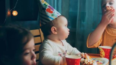 Bir yaşındaki kızların doğum günü partisi. Annem bir tabak kek getiriyor. Kız kardeşler pastayı seve seve yer ve pastayla kirlenirler. Annem tatilini telefonuyla çekiyor..