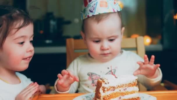 1歳の女の子の誕生日パーティー お母さんはケーキを持ってくる 姉妹は喜んでケーキを食べ ケーキに汚れてしまいます 母は電話で休暇を撮影しています — ストック動画