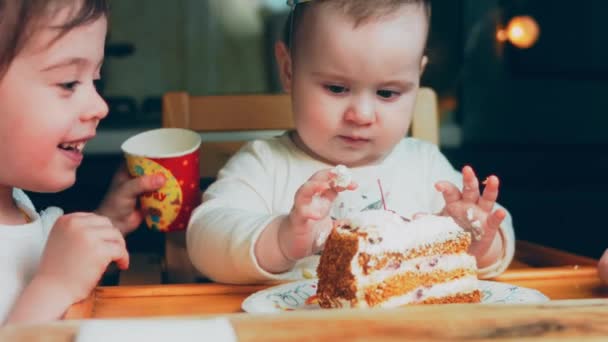 1歳の女の子の誕生日パーティー お母さんはケーキを持ってくる 姉妹は喜んでケーキを食べ ケーキに汚れてしまいます 母は電話で休暇を撮影しています — ストック動画