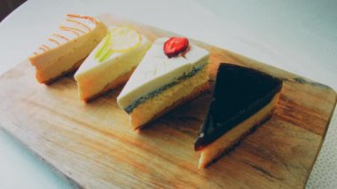 Arka arkaya dizilmiş dört çeşit cheesecake. Kaypak ve makro atış. Bir retro stil pişirme tahtası kullanılır.