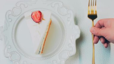 Retro tabakta limonlu cheesecake. Altın çatal ve bıçak kullan. Kız çatalla bir parça kek yiyor. Arka plandaki kız eğleniyor. Doğum gününü kutluyoruz. Yavaş çekim.