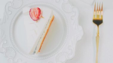 Retro tabakta limonlu cheesecake. Altın çatal ve bıçak kullan. Kız çatalla bir parça kek yiyor. Arka plandaki kız eğleniyor. Doğum gününü kutluyoruz. Yavaş çekim.