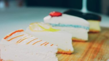 Arka arkaya dizilmiş dört çeşit cheesecake. Kaypak ve makro atış. Bir retro stil pişirme tahtası kullanılır.