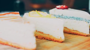 Arka arkaya dizilmiş dört çeşit cheesecake. Kaypak ve makro atış. Bir retro stil pişirme tahtası kullanılır.