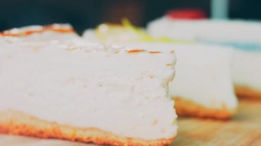 Arka arkaya dizilmiş dört çeşit cheesecake. Kaypak ve makro atış. Bir retro stil pişirme tahtası kullanılır.