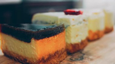 Arka arkaya dizilmiş dört çeşit cheesecake. Kaypak ve makro atış. Bir retro stil pişirme tahtası kullanılır.