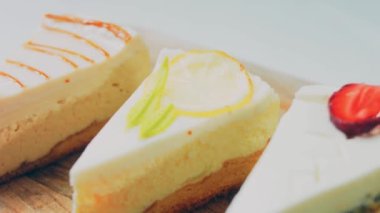 Arka arkaya dizilmiş dört çeşit cheesecake. Kaypak ve makro atış. Bir retro stil pişirme tahtası kullanılır.