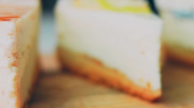 Arka arkaya dizilmiş dört çeşit cheesecake. Kaypak ve makro atış. Bir retro stil pişirme tahtası kullanılır.