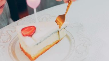 Retro tabakta limonlu cheesecake. Altın çatal ve bıçak kullan. Kız çatalla bir parça kek yiyor. Arka plandaki kız eğleniyor. Doğum gününü kutluyoruz. Yavaş çekim.