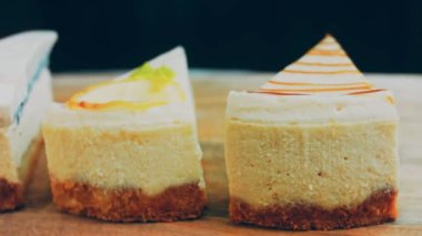 Arka arkaya dizilmiş dört çeşit cheesecake. Kaypak ve makro atış. Bir retro stil pişirme tahtası kullanılır.