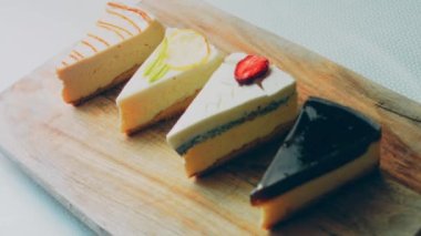 Arka arkaya dizilmiş dört çeşit cheesecake. Kaypak ve makro atış. Bir retro stil pişirme tahtası kullanılır.