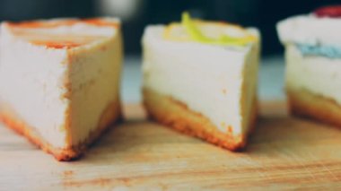 Arka arkaya dizilmiş dört çeşit cheesecake. Kaypak ve makro atış. Bir retro stil pişirme tahtası kullanılır.