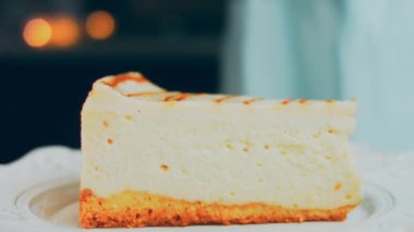 Retro tabakta limonlu cheesecake. Altın çatal ve bıçak kullan. Kız çatalla bir parça kek yiyor. Arka plandaki kız eğleniyor. Doğum gününü kutluyoruz. Yavaş çekim.