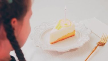 Retro tabakta limonlu cheesecake. Altın çatal ve bıçak kullan. Kız çatalla bir parça kek yiyor. Arka plandaki kız eğleniyor. Doğum gününü kutluyoruz. Yavaş çekim.