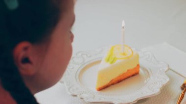 Retro tabakta limonlu cheesecake. Altın çatal ve bıçak kullan. Kız çatalla bir parça kek yiyor. Arka plandaki kız eğleniyor. Doğum gününü kutluyoruz. Yavaş çekim.