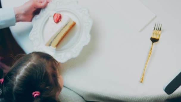 レトロなプレートの上にレモンチーズケーキ 金のフォークとナイフを使用してください 女の子はフォークでケーキを食べている 背景の女の子は楽しんでいる 誕生日を祝います スローモーション — ストック動画