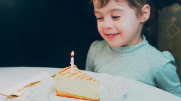 レトロなプレートにキャラメルチーズケーキ 金のフォークとナイフを使用してください ケーキの上の燃えるろうそくを消しなさい 誕生日を祝います — ストック動画