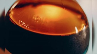 Pouring cola into a glass. Filling glass with fizzy cola. Lens light reflections in close up slow motion shot 500FPS Glass of Cola with fizzy baubles isolated on black background