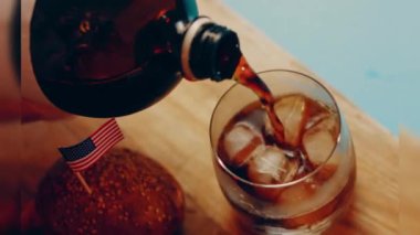 Pouring cola into a glass. Filling glass with fizzy cola. Lens light reflections in close up slow motion shot 500FPS Glass of Cola with fizzy baubles isolated on black background