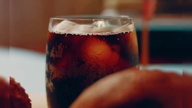 Pouring cola into a glass. Filling glass with fizzy cola. Lens light reflections in close up slow motion shot 500FPS Glass of Cola with fizzy baubles isolated on black background
