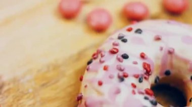 Tatlılarla süslenmiş pembe çörekler. Makro ve kaydırma atışı. Tatlı, jöleli tatlılar. Fırın ve yemek konsepti. Çeşitli renkli çörekler. Çikolata, pembe, mavi çörekler 4K, UHD.