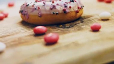 Tatlılarla süslenmiş pembe çörekler. Makro ve kaydırma atışı. Tatlı, jöleli tatlılar. Fırın ve yemek konsepti. Çeşitli renkli çörekler. Çikolata, pembe, mavi çörekler 4K, UHD.