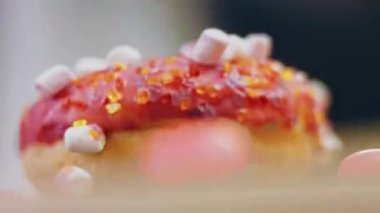 Marshmello ile süslenmiş pembe çörekler. Makro ve kaydırma atışı. Fırın ve yemek konsepti. Çeşitli renkli çörekler. Çikolata, pembe, mavi çörekler 4K, UHD.