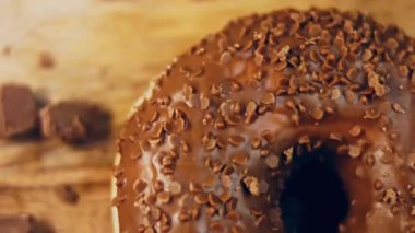 Çikolatalı çörekler çikolata parçalarıyla süslenmiş. Donutlar doğal çikolatayla süslenmiş bir kağıdın üzerinde. Makro ve kaydırma atışı. Fırın ve yemek konsepti. Çeşitli renkli çörekler. Çikolata, pembe