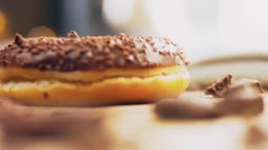 Çikolatalı çörekler çikolata parçalarıyla süslenmiş. Donutlar doğal çikolatayla süslenmiş bir kağıdın üzerinde. Makro ve kaydırma atışı. Fırın ve yemek konsepti. Çeşitli renkli çörekler. Çikolata, pembe