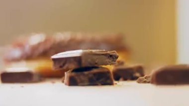 Çikolatalı çörekler çikolata parçalarıyla süslenmiş. Donutlar doğal çikolatayla süslenmiş bir kağıdın üzerinde. Makro ve kaydırma atışı. Fırın ve yemek konsepti. Çeşitli renkli çörekler. Çikolata, pembe