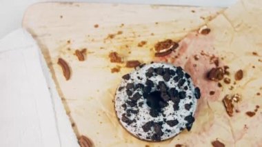 Oeo bisküvileriyle süslenmiş çikolatalı çörekler. Donutlar doğal çikolatayla süslenmiş bir kağıdın üzerinde. Makro ve kaydırma atışı. Fırın ve yemek konsepti. Çeşitli renkli çörekler. Çikolata.