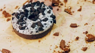 Oeo bisküvileriyle süslenmiş çikolatalı çörekler. Donutlar doğal çikolatayla süslenmiş bir kağıdın üzerinde. Makro ve kaydırma atışı. Fırın ve yemek konsepti. Çeşitli renkli çörekler. Çikolata.